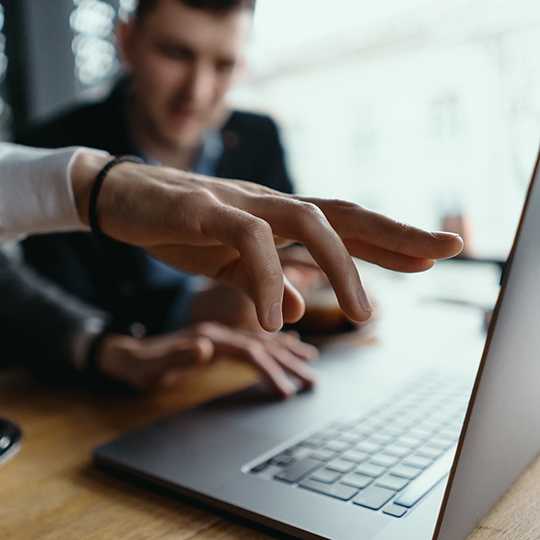 Two businessmen pointing laptop screen while discussing